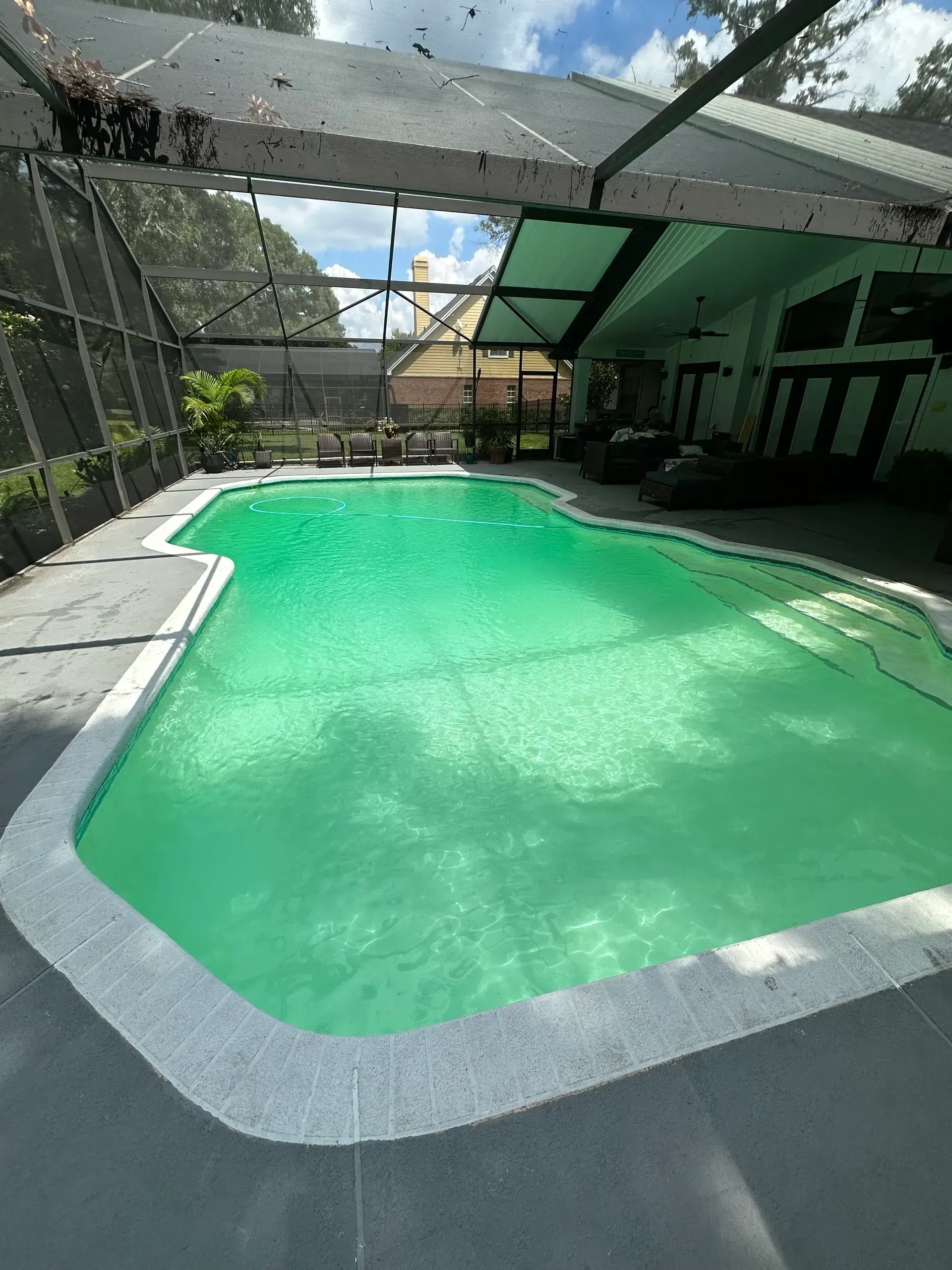 A large swimming pool with a screened in area in the backyard of a house.