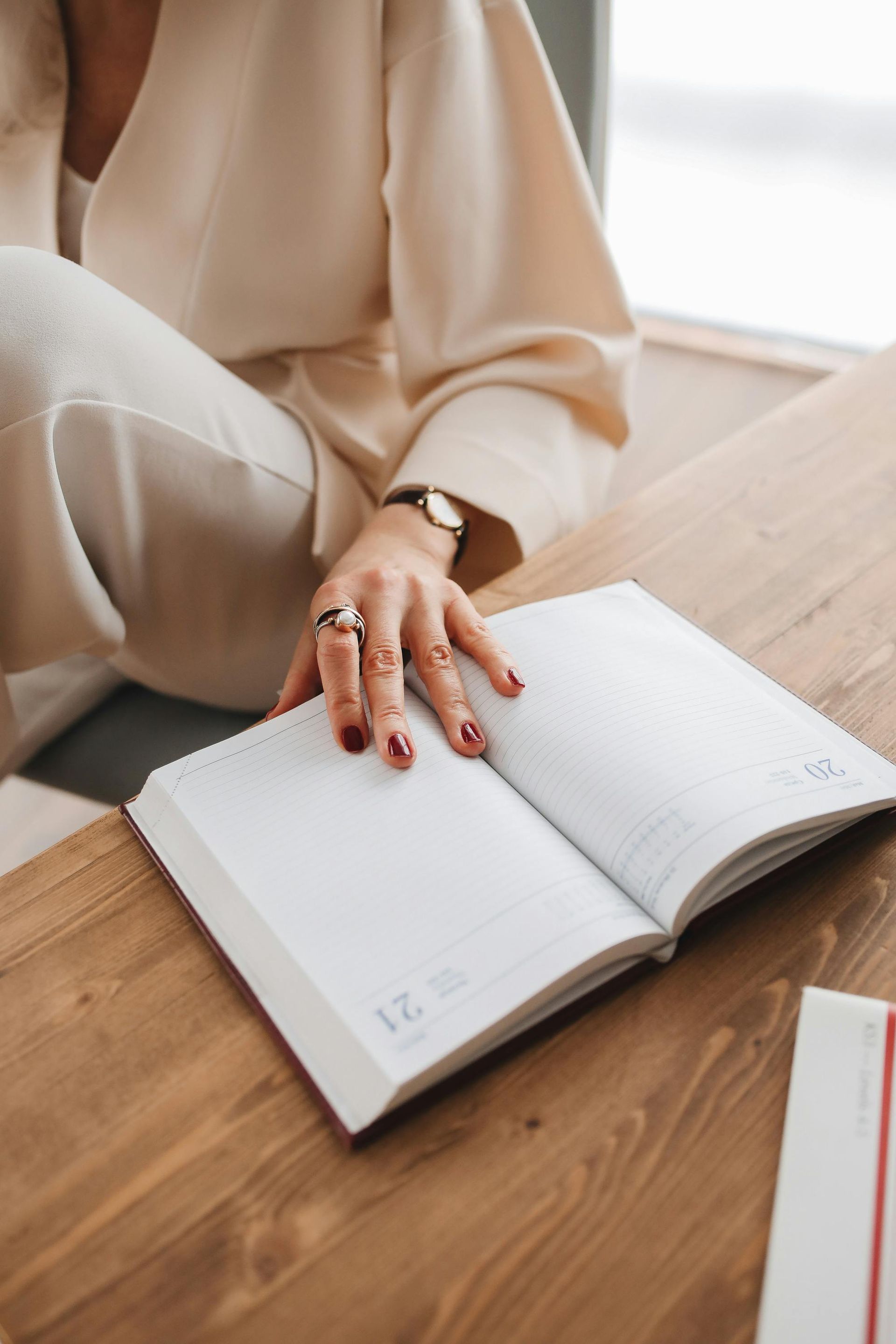 A woman is sitting at a table reading a book.