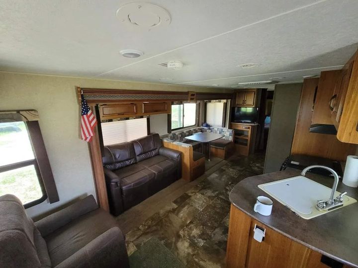 RV interior with kitchen, dining bench, couch, and large windows