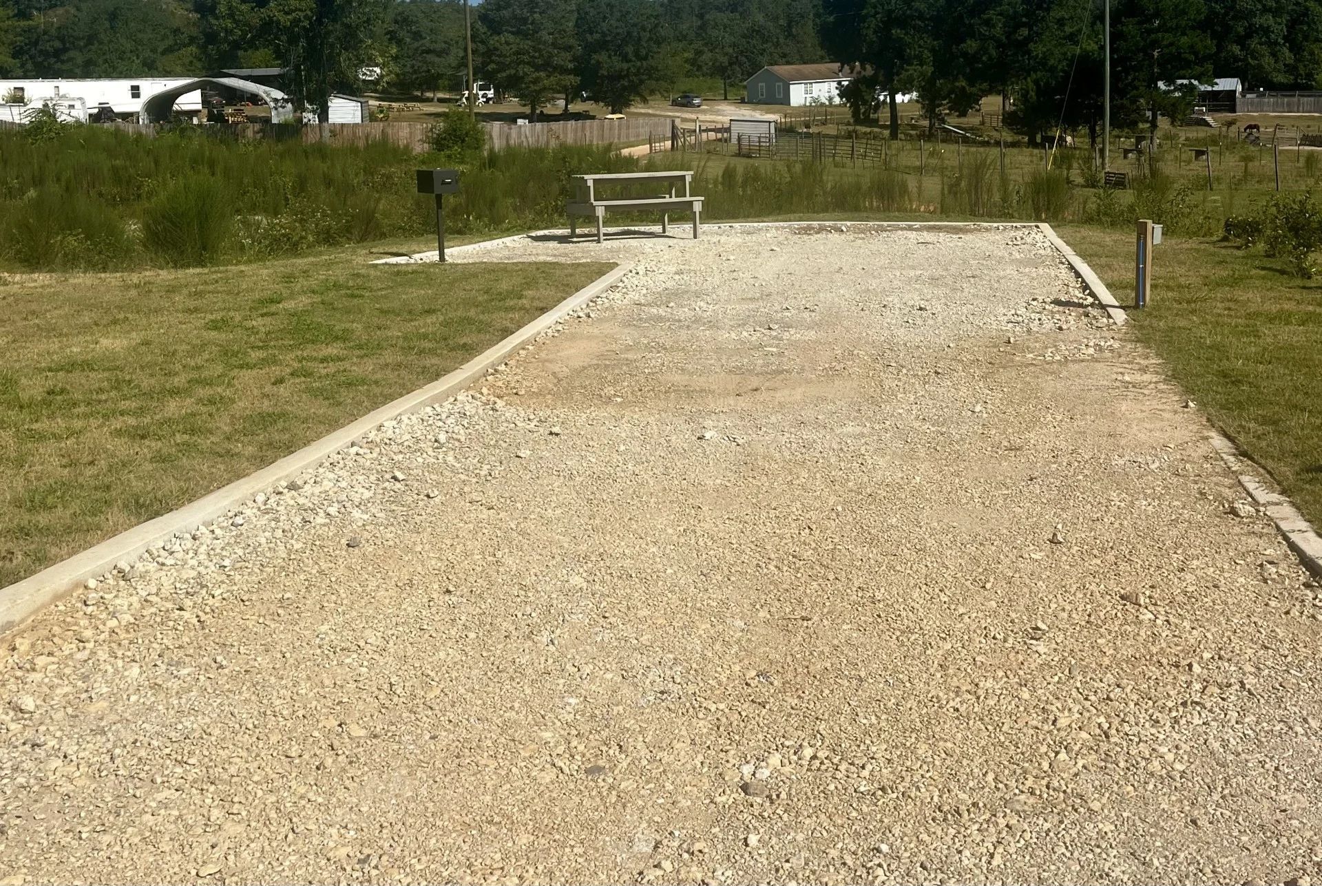 Gravel pathway leading to a bench in a grassy park under clear daylight
