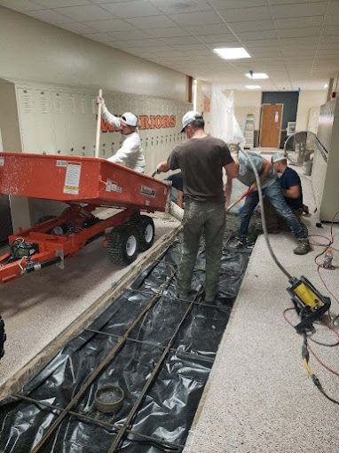 A group of men are working on a plumbing install in a school hallway