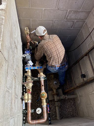 A Plumber is working on a water meter in a basement.