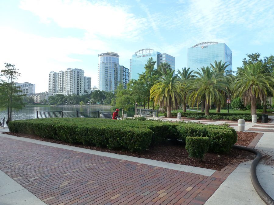 A brick walkway in a park with tall buildings in the background