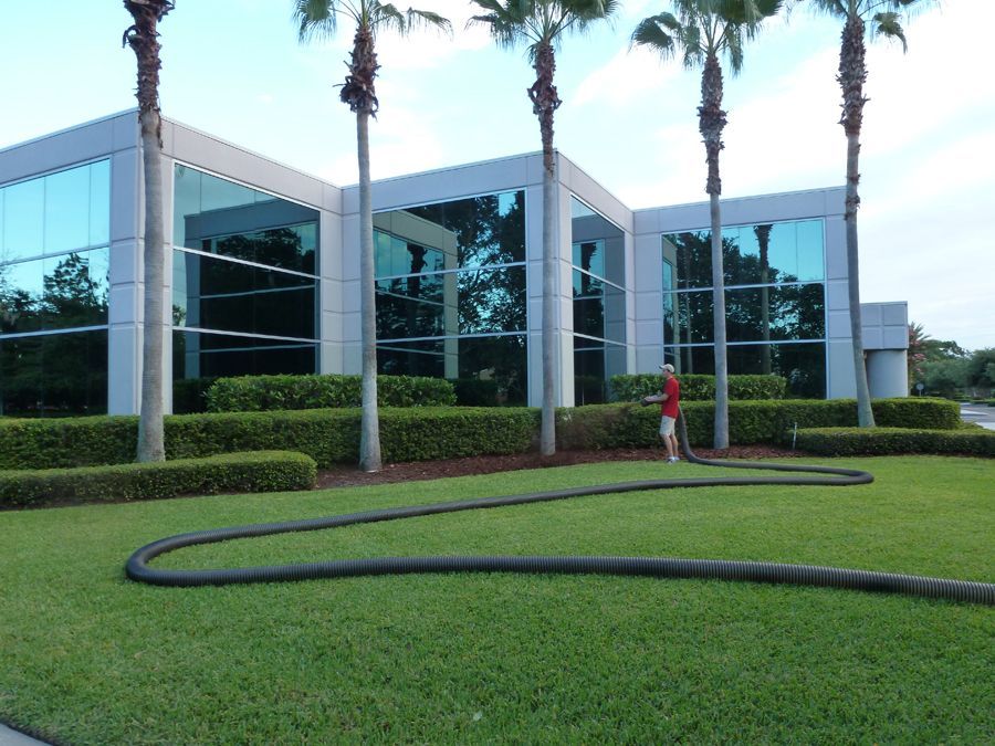 A man in a red shirt is standing in front of a large building