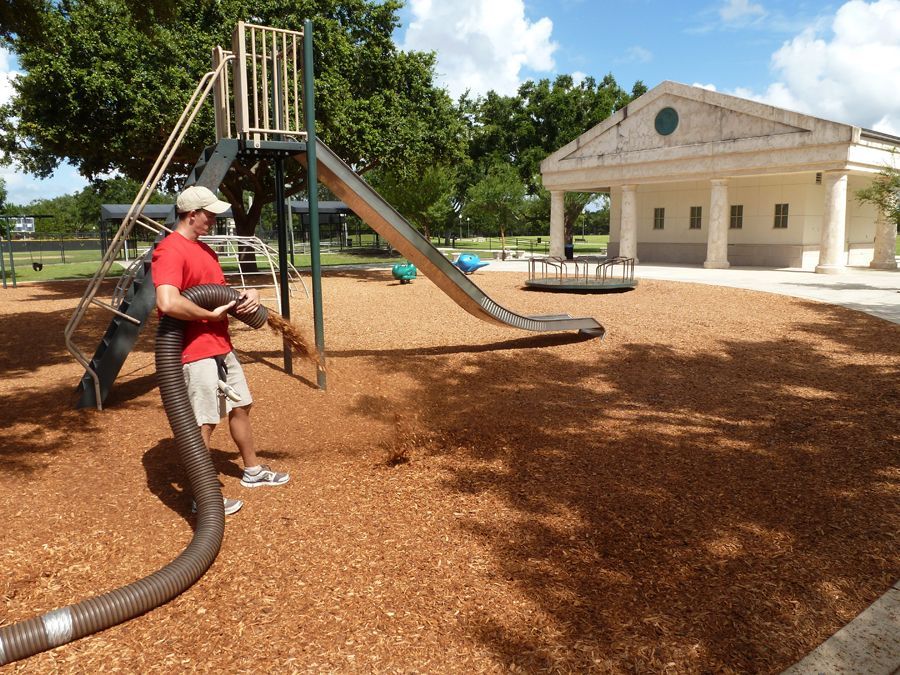 A man in a red shirt is standing in front of a slide in a park