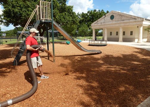 A man is using a vacuum hose to clean a playground