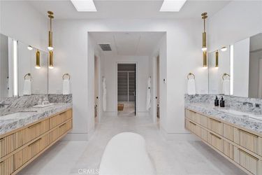 A bathroom with two sinks , two mirrors and a bathtub.