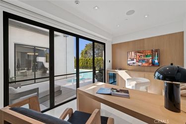A living room with a desk and chairs and a large window