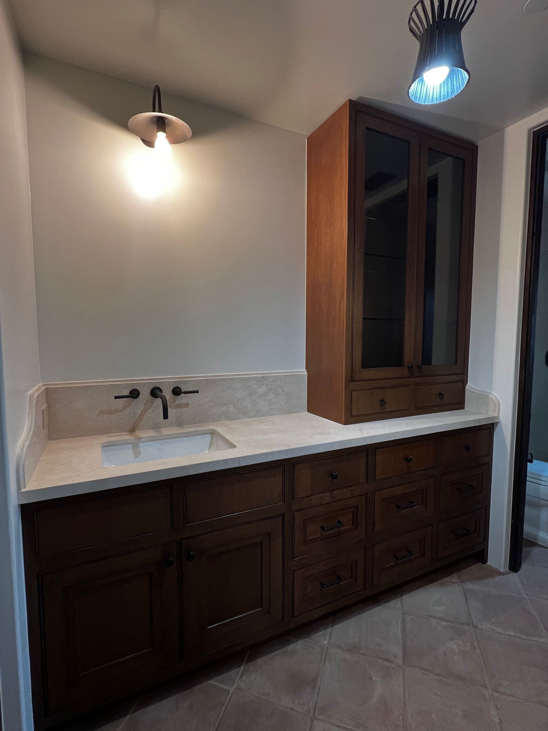A bathroom with a sink , cabinets and a light on the ceiling.