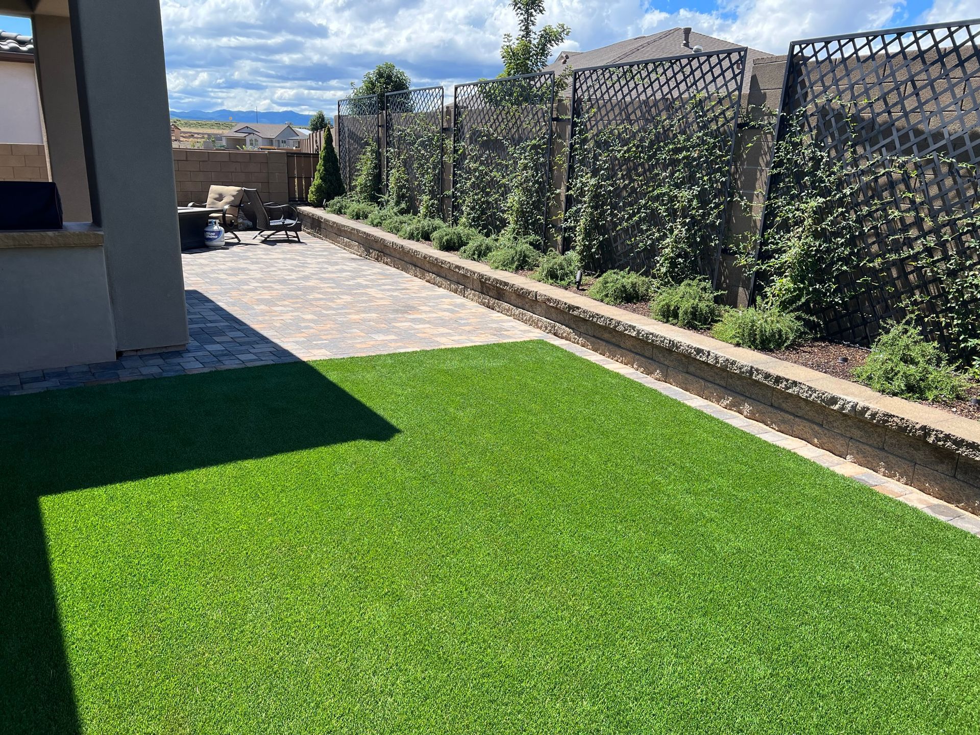 A backyard with a lot of green grass and a fence.