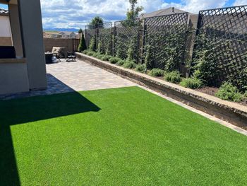 A backyard with a lot of green grass and a fence.