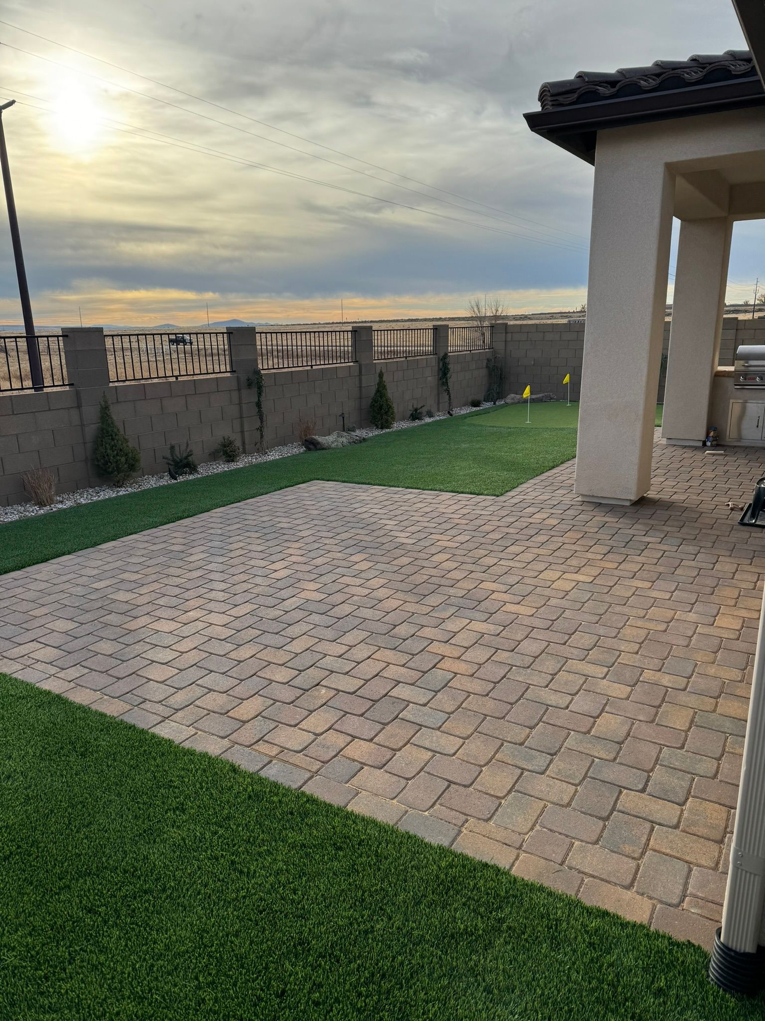 There is a brick walkway leading to a patio with a view of the ocean.