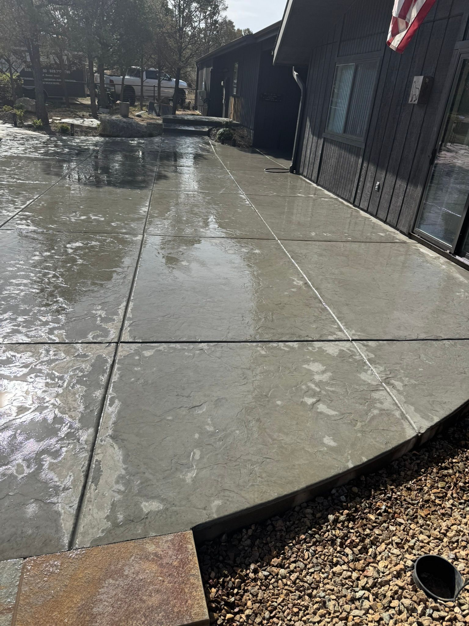 A concrete walkway next to a house with water coming out of it.