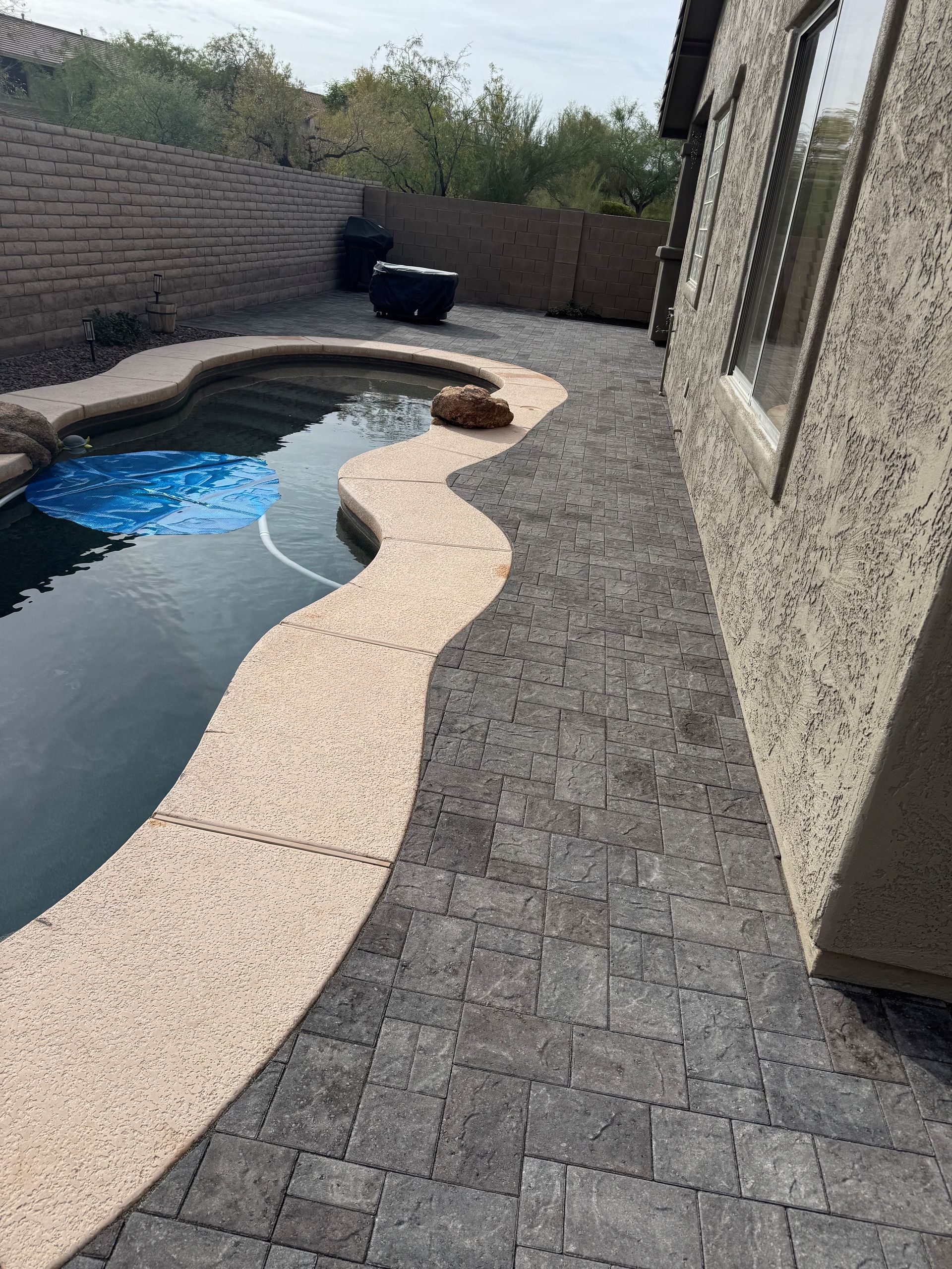 A walkway leading to a swimming pool next to a house.