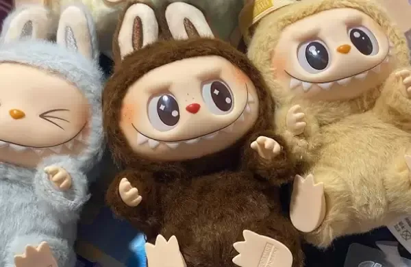Tres juguetes de peluche: criaturas con capucha de conejo, ojos grandes, bocas abiertas y cuerpos peludos.