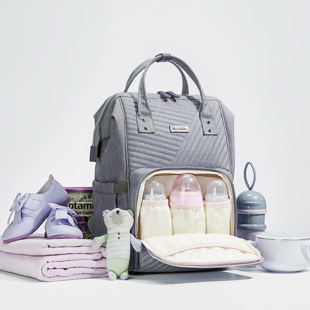 Bolsa de pañales acolchada gris con biberones, artículos para bebé y accesorios.