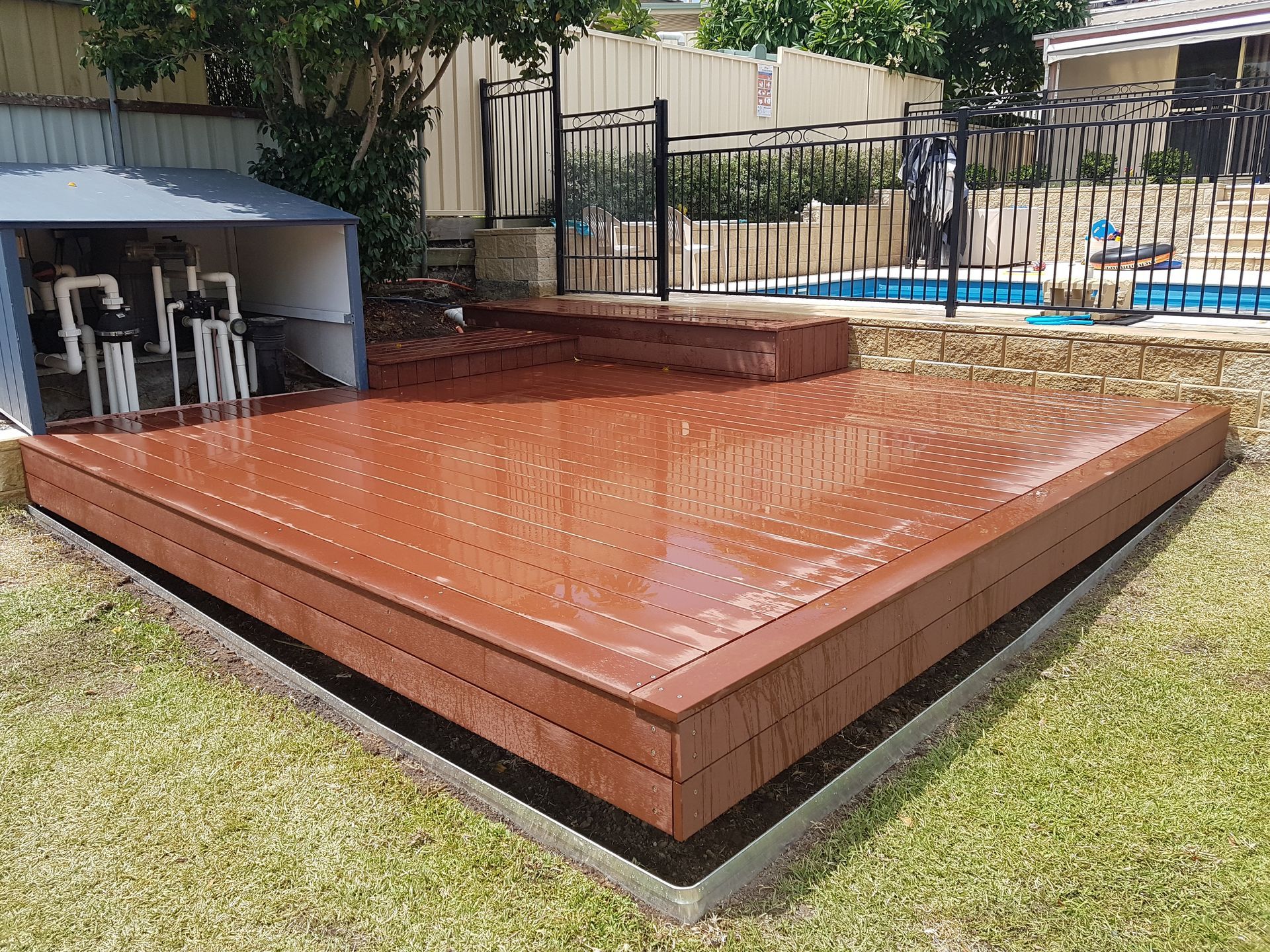 Gray Composite Deck in a Backyard Next to a Concrete Patio — Creating Eden Landscaping In Speers Point, NSW