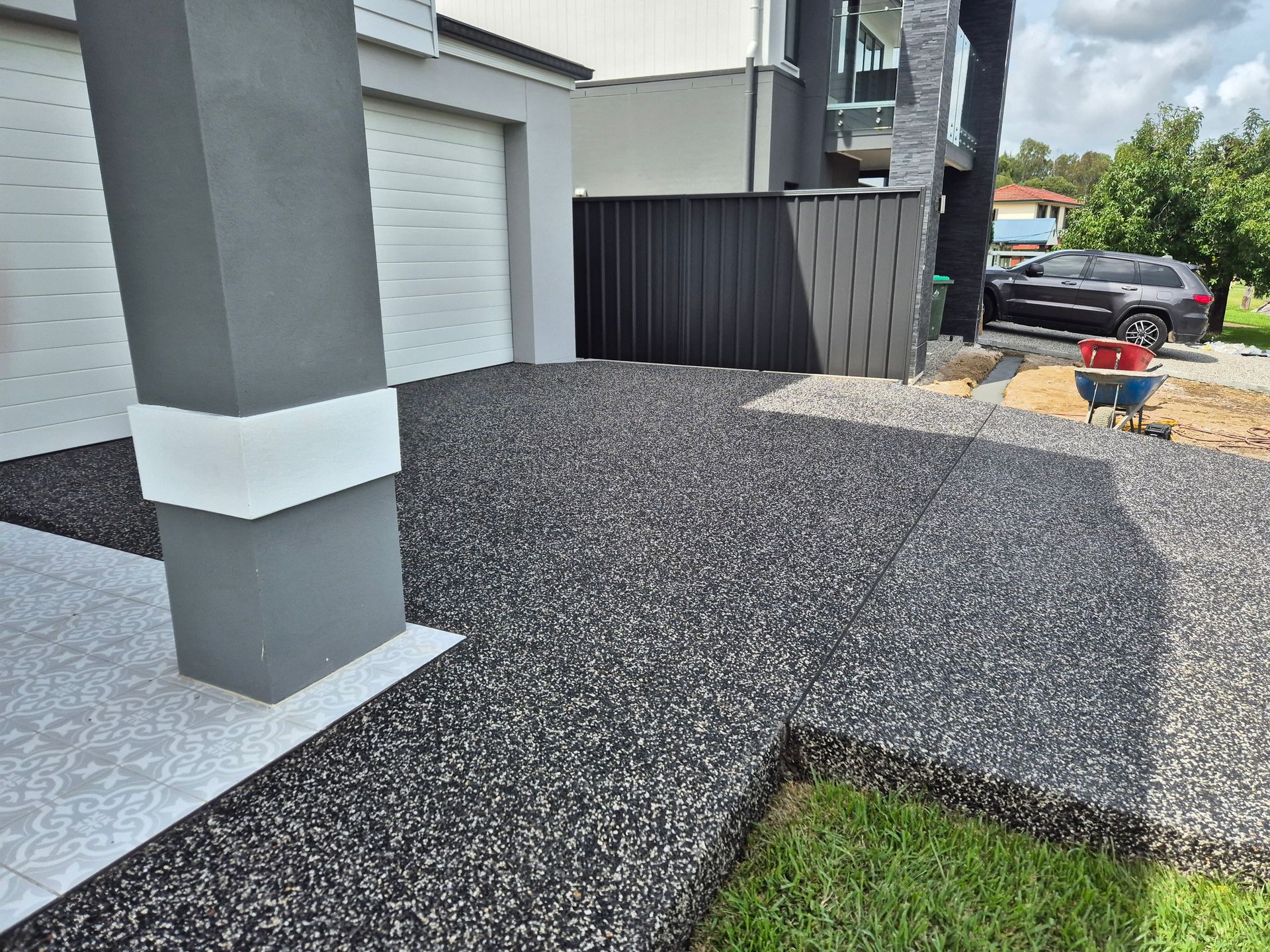 A landscaped backyard with paving, brick borders, a small tree, and a person working.