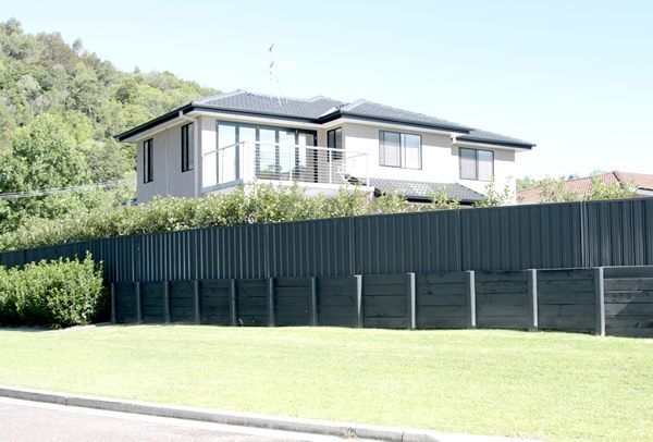 A Large House with A Black Fence Surrounding It — Creating Eden Landscaping In Edgeworth, NSW