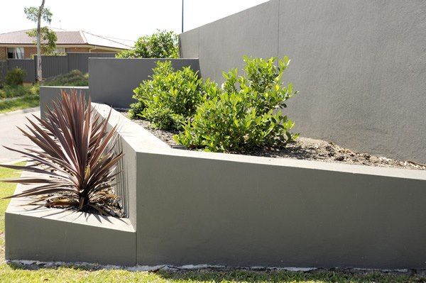 A Planter with Plants in It Is Sitting Next to A Wall — Creating Eden Landscaping In Edgeworth, NSW