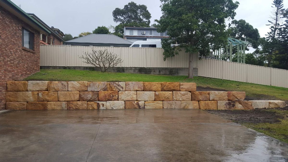 A Stone Wall Is Being Built in Front of A House — Creating Eden Landscaping In Boolaroo, NSW