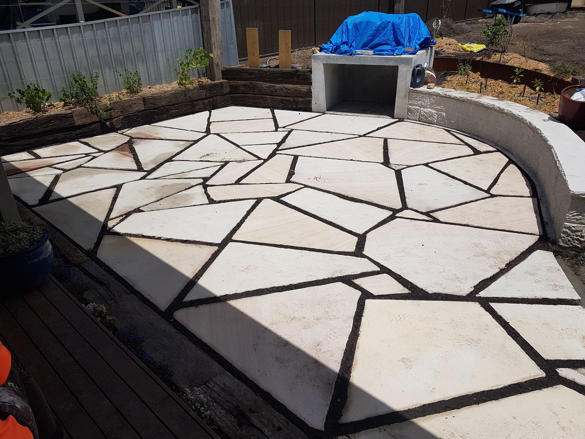 Patio with flagstone pavers, a built-in fireplace, and retaining walls in an outdoor setting.