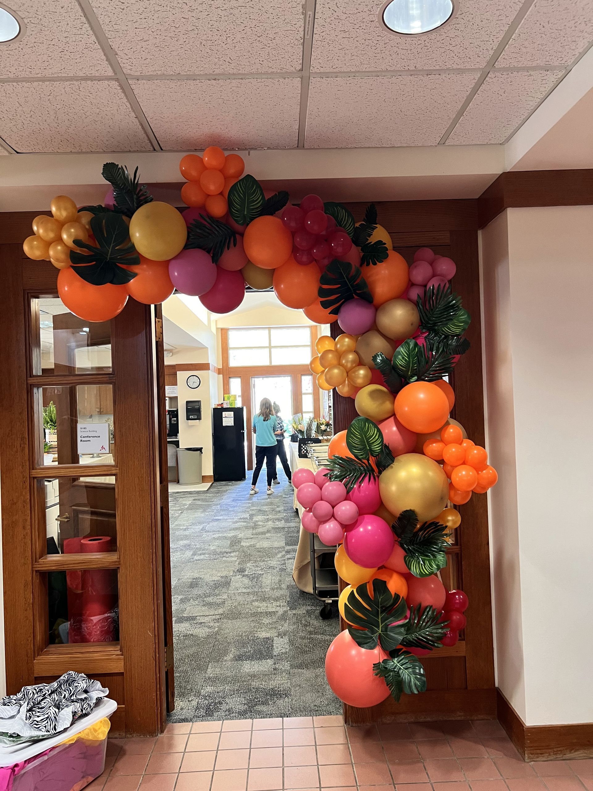 A balloon arch is hanging over a doorway in a room.