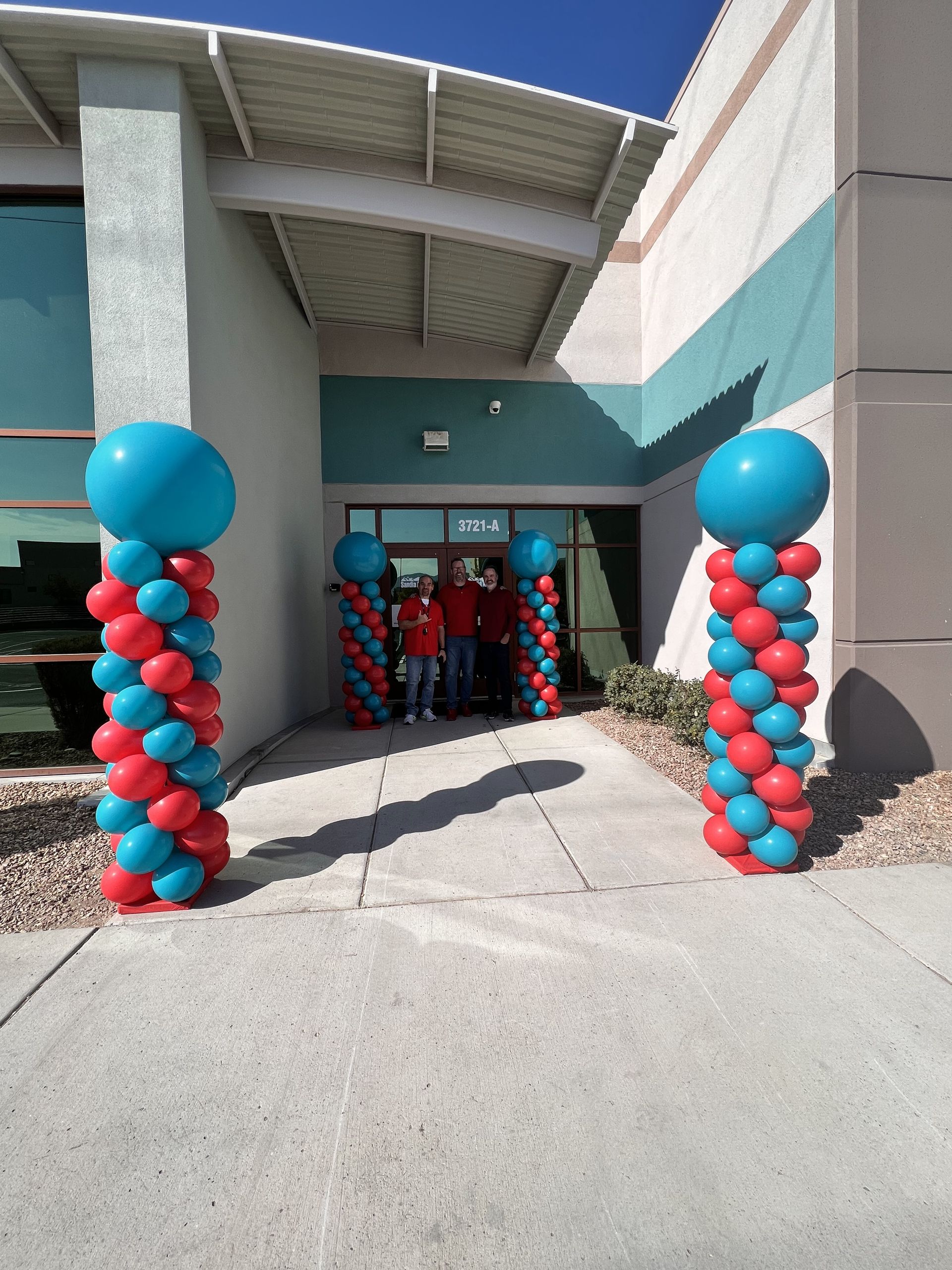 Red and blue balloons are lined up in front of a building