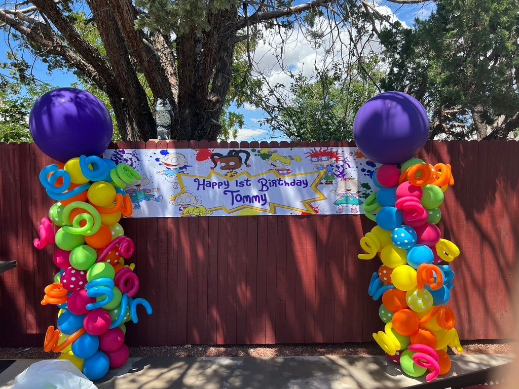 A bunch of colorful balloons are sitting on top of a wooden fence.