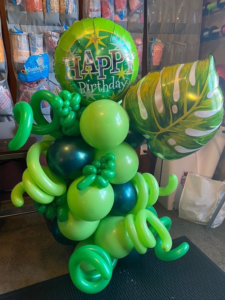 A bunch of green balloons are sitting on top of each other on a table.