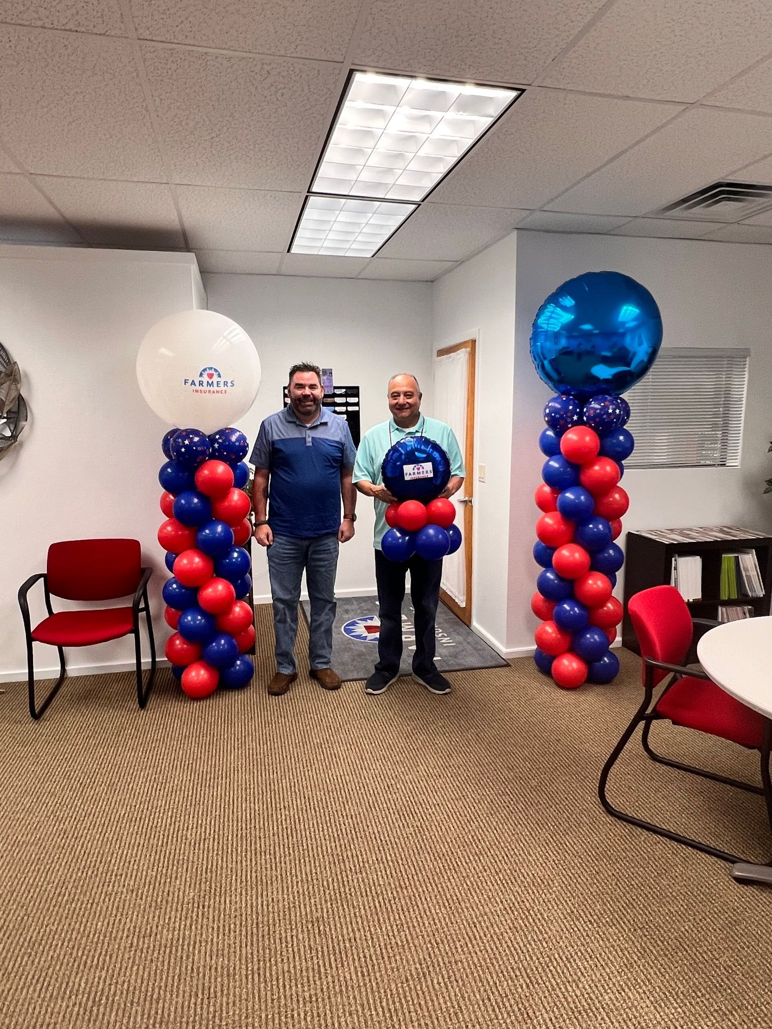 Two men are standing next to balloon columns in a room.
