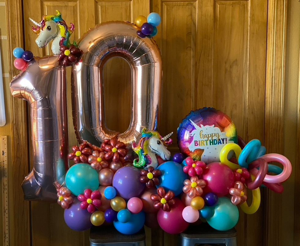 A bunch of balloons are sitting on a table in front of a wooden door.