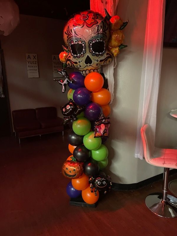 A balloon tower with a sugar skull on top of it.