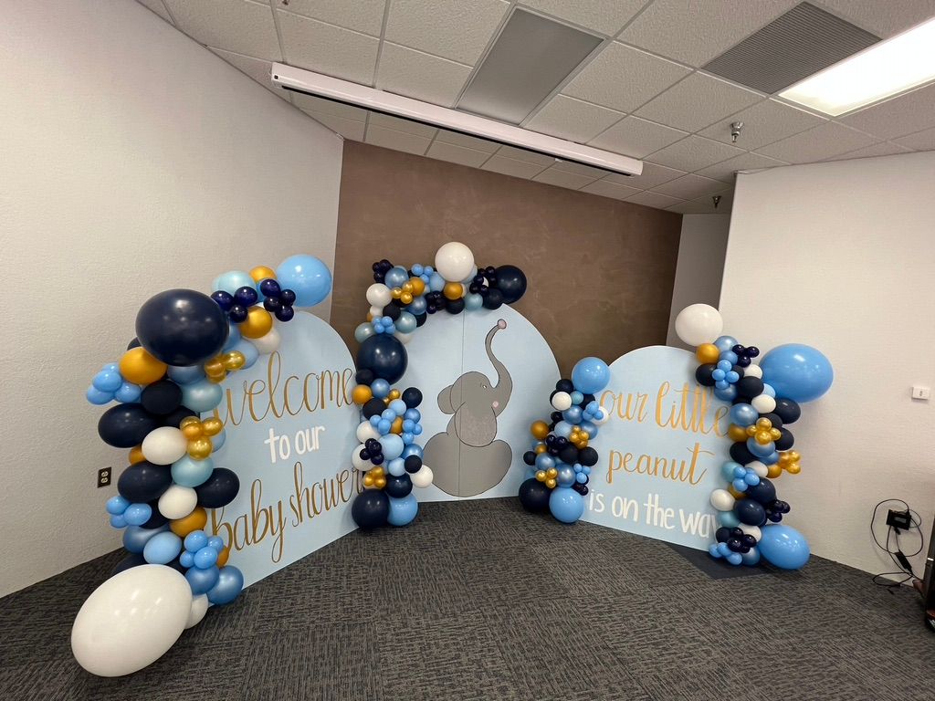 A room decorated with blue and gold balloons for a baby shower.