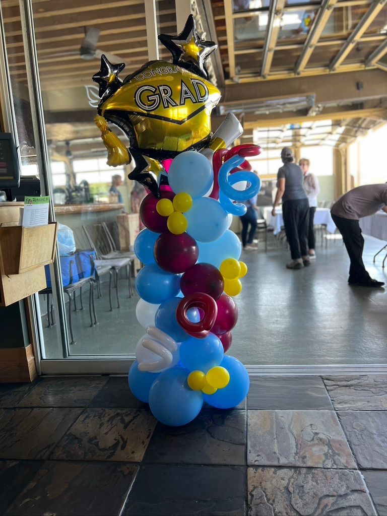A balloon tower is sitting on a tiled floor in a room.