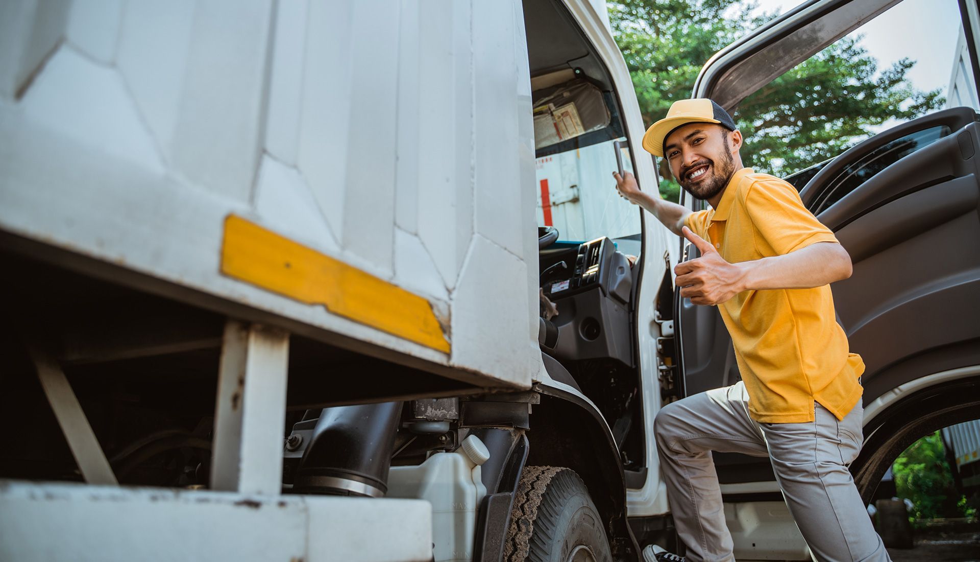 Man in yellow shirt exiting truck, giving thumbs up.