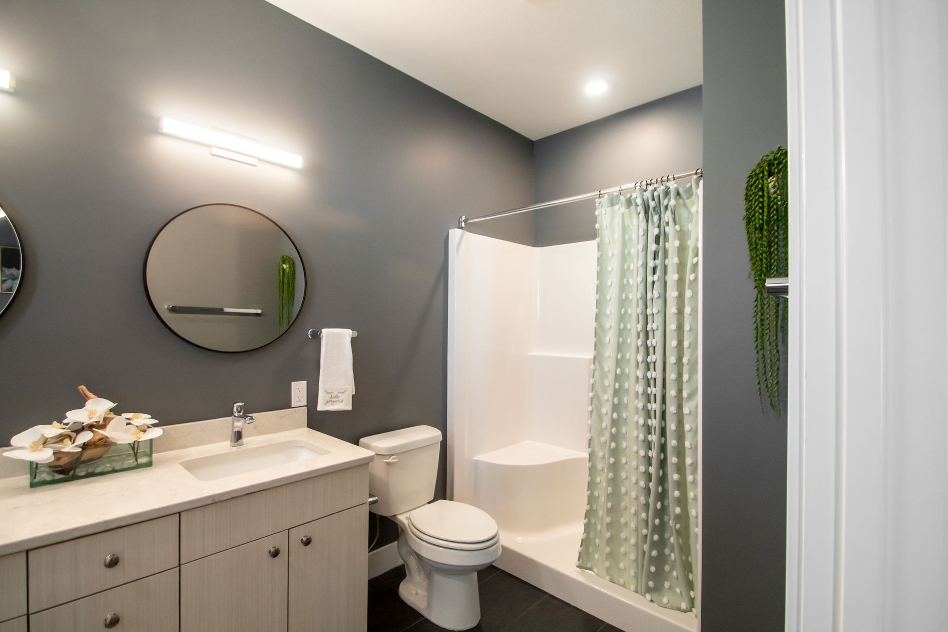 A bathroom with a sink , toilet , shower and mirror.