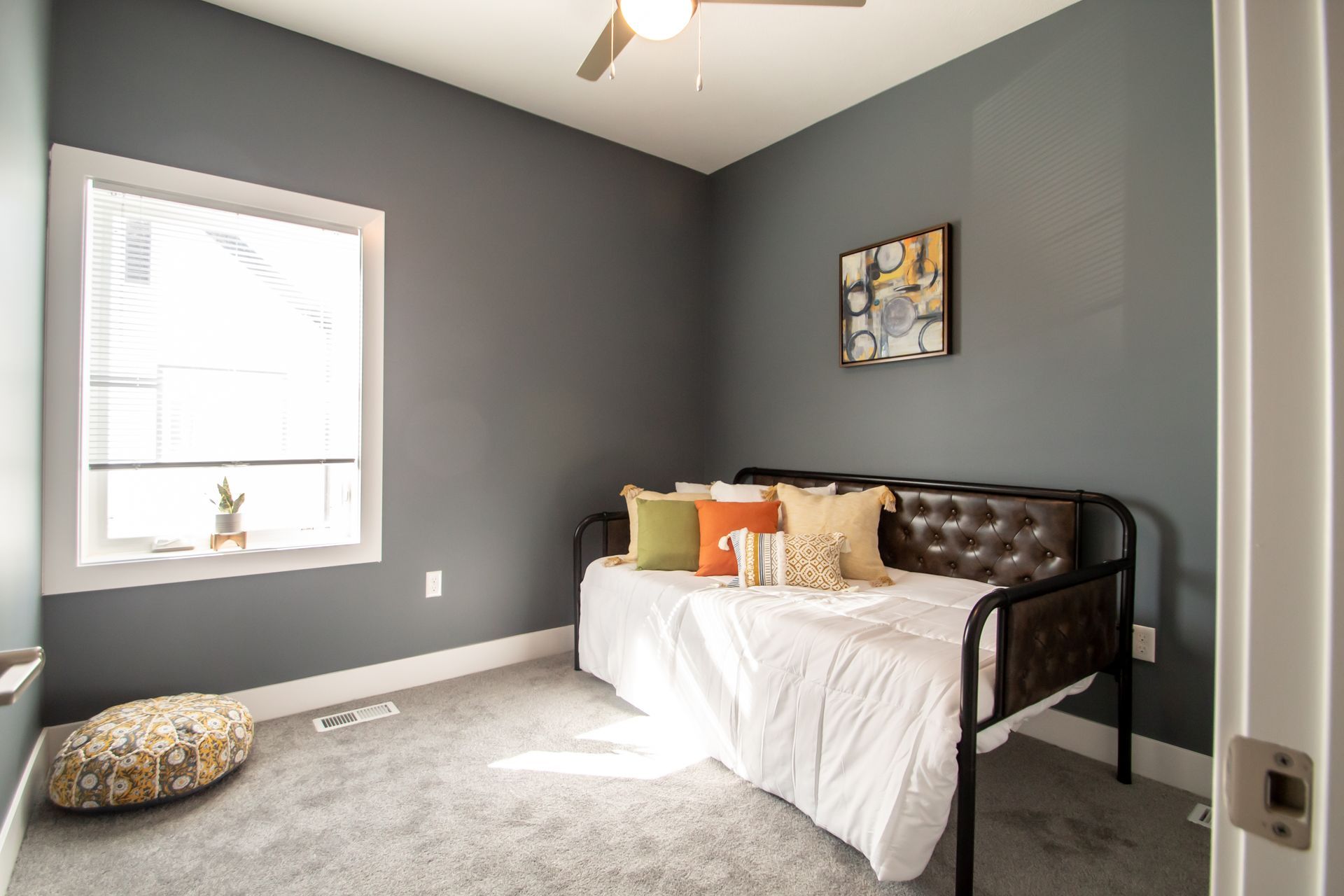A bedroom with a day bed and a window.