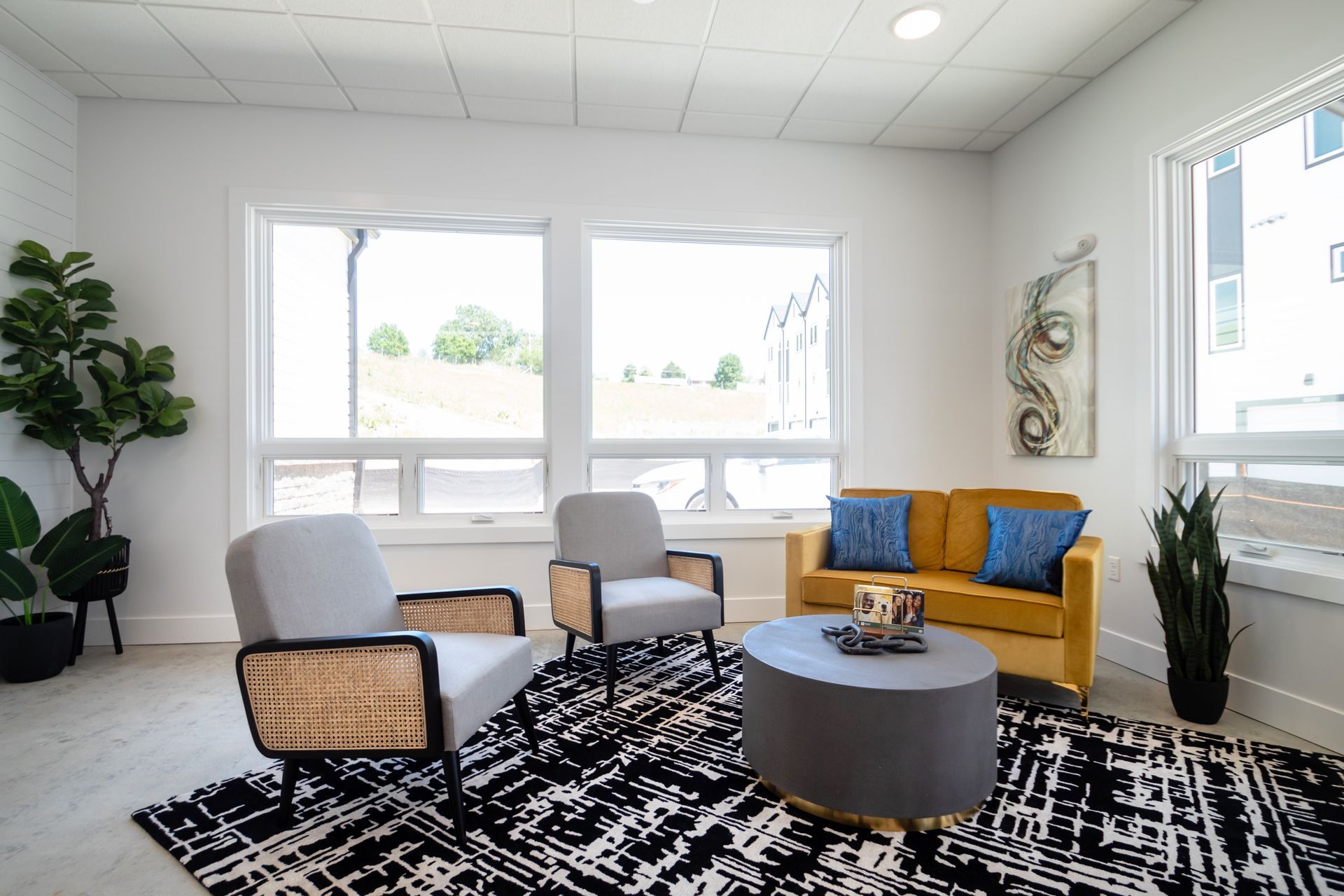 A living room with a yellow couch , two chairs , a coffee table and a rug.