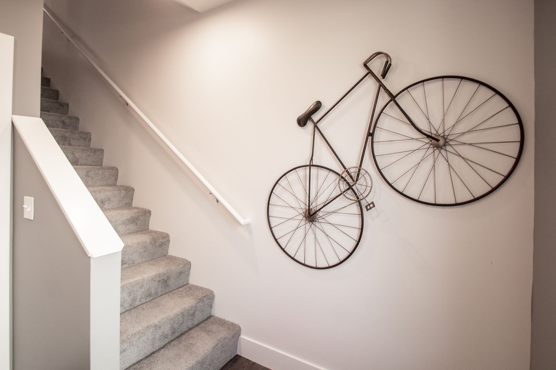 A bicycle is hanging on a wall next to a set of stairs.