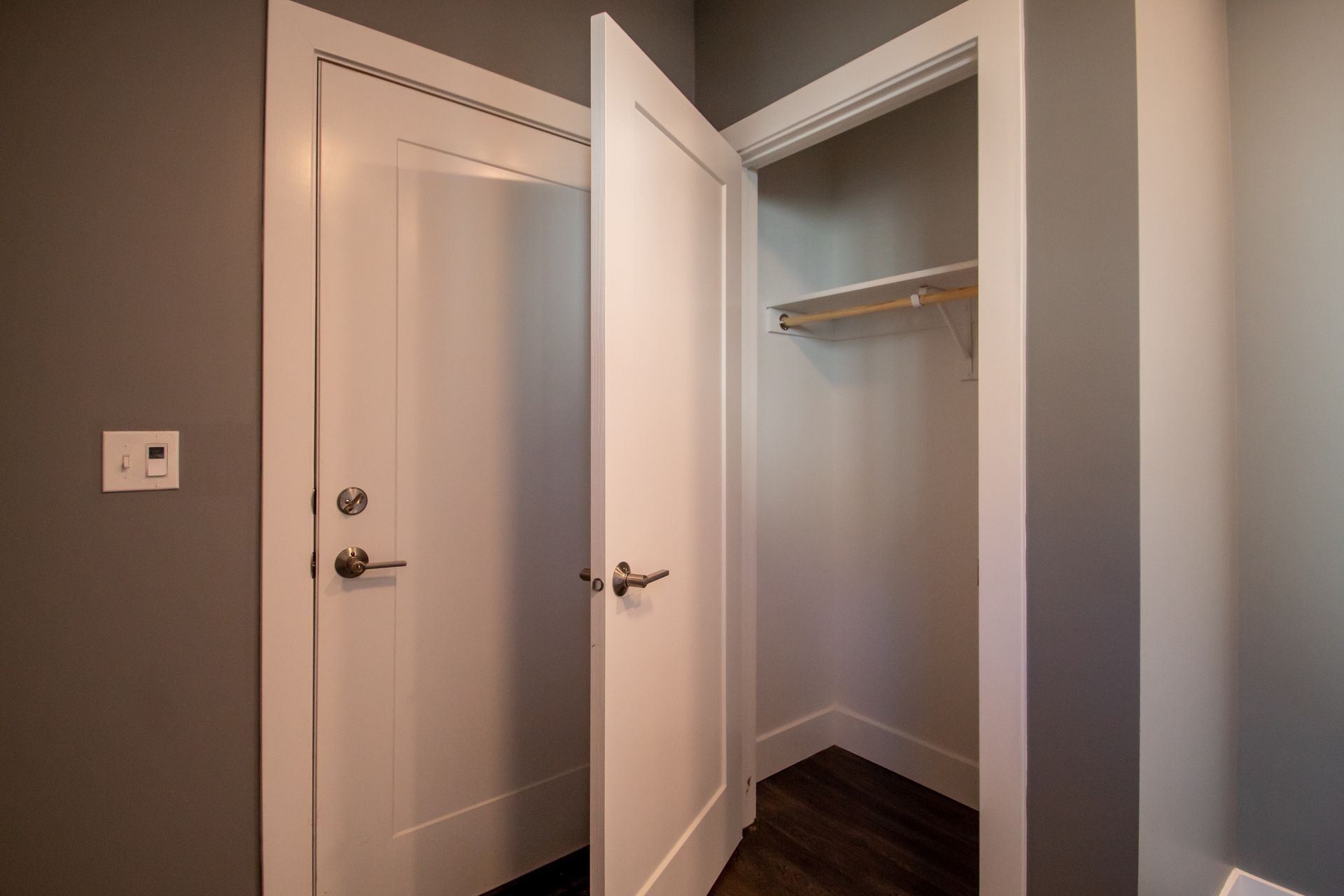 A walk in closet with a door open and a shelf.