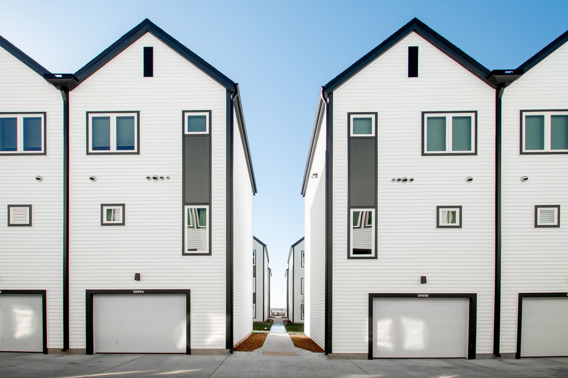 A row of white houses with black roofs and garages.