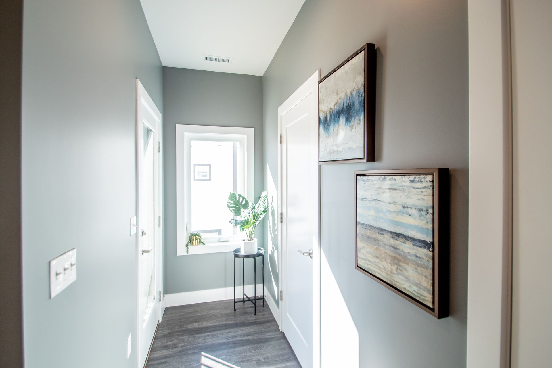 A hallway with paintings on the wall and a window.