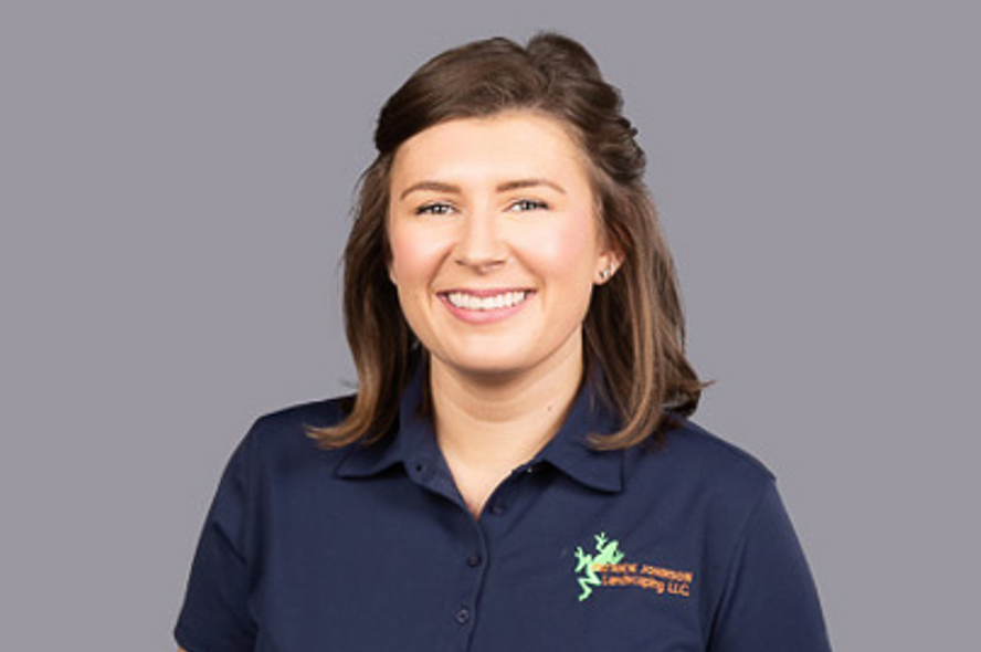 A woman in a blue shirt is smiling for the camera.