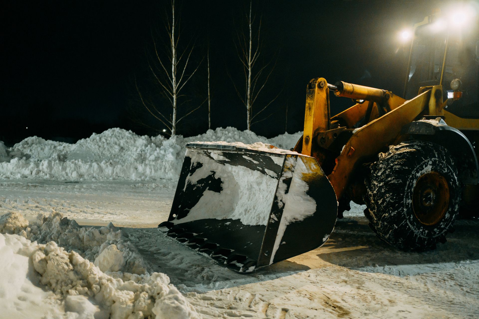 A snow plow is clearing snow from the road at night.