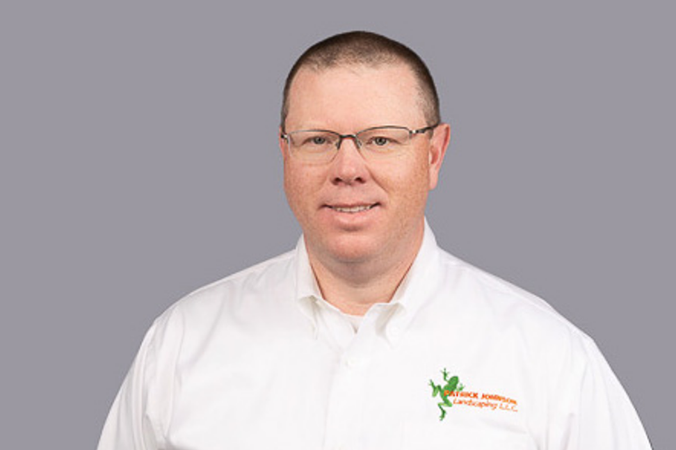 A man wearing glasses and a white shirt is smiling for the camera.