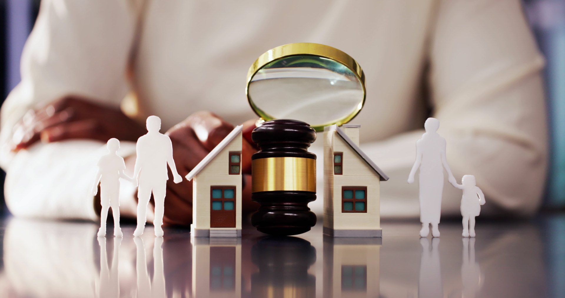 A woman is sitting at a table with a magnifying glass , a gavel , and paper people.