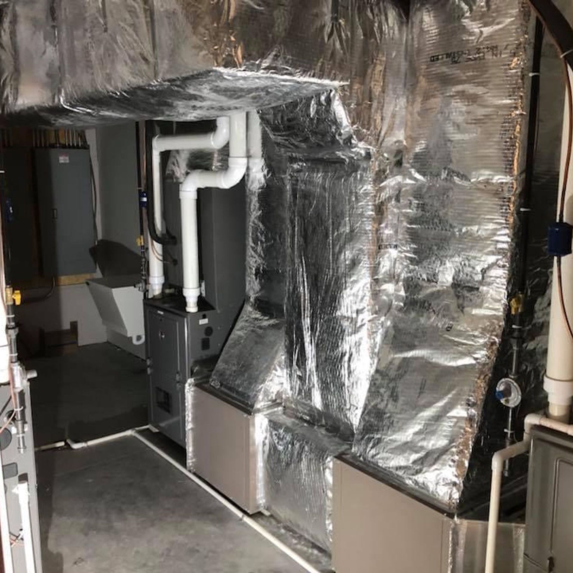 Lake Area Heating and Cooling LLC | A room with a furnace and pipes covered in aluminum foil.