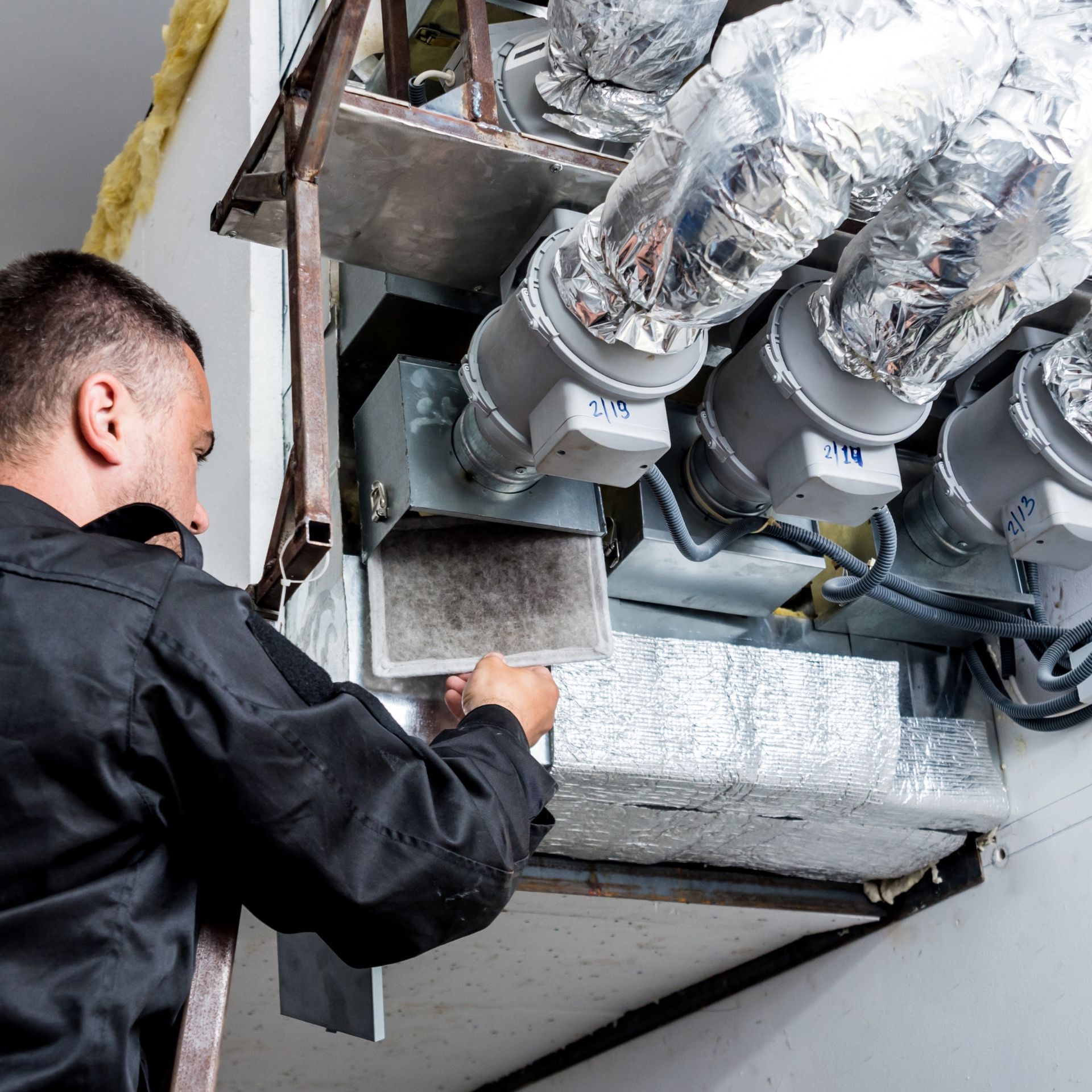 Lake Area Heating and Cooling LLC | A man is working on a ventilation system in a building.