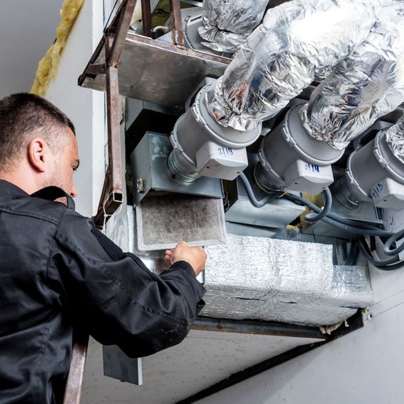 Lake Area Heating and Cooling LLC | A man is working on a ventilation system in a building